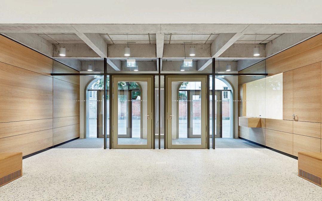Die Kubatur des Baus respektierend, wird der Windfang als Holz-Glas-Konstruktion ins Innere gezogen. Das großzügige Foyer ist von unprätentiöser und doch würdiger Gestaltung, das Selbstverständnis der Institution Amtsgericht zum Ausdruck bringend. Fotografie: Dietmar Strauß, Besigheim