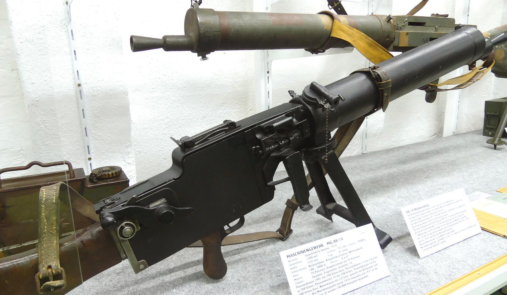Die Redewendung 08/15 geht auf das Einheits-Maschinengewehr aus dem Ersten Weltkrieg zurück (vorne). 08 steht für das Jahr der Einführung, 15 für das Jahr der Weiterentwicklung. Wegen des eintönigen Trainings an der Waffe und der zu Kriegszeiten abnehmenden Materialqualität bekam „08/15“ eine abwertende Bedeutung. Das Holzgewehr dahinter diente Übungszwecken. Die Redewendung 08/15 geht auf das Einheits-Maschinengewehr aus dem Ersten Weltkrieg zurück (vorne). 08 steht für das Jahr der Einführung, 15 für das Jahr der Weiterentwicklung. Wegen des eintönigen Trainings an der Waffe und der zu Kriegszeiten abnehmenden Materialqualität bekam „08/15“ eine abwertende Bedeutung. Das Holzgewehr dahinter diente Übungszwecken.