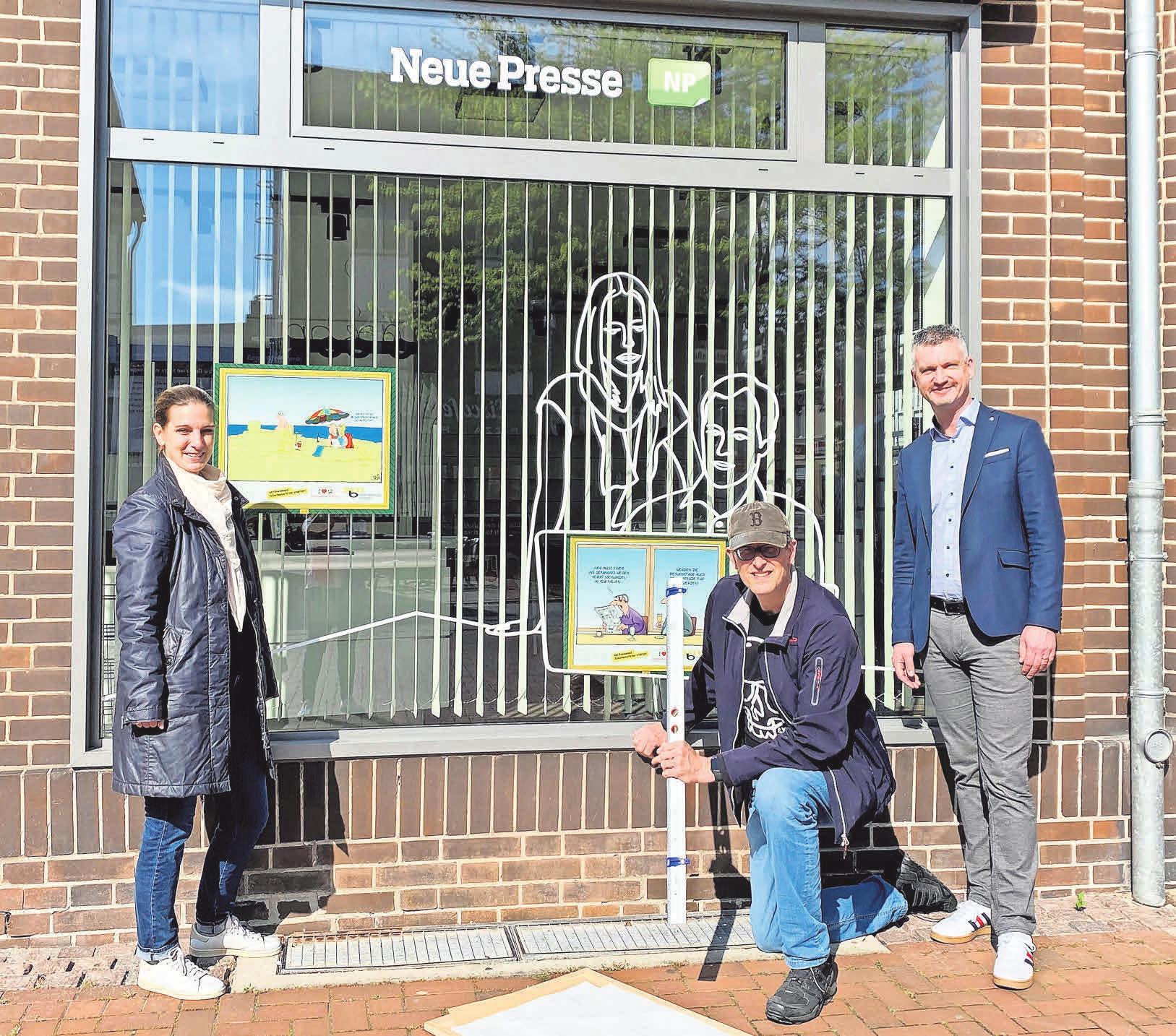 Katja Weberling vom Stadtmarketing, Galerist Bernd Schönebaum (von links) und Madsack-Verkaufsleiter Carsten Hanisch befestigen Cartoons am Schaufenster der HAZ/NP/Marktspiegel-Geschäftsstelle. Katja Weberling vom Stadtmarketing, Galerist Bernd Schönebaum (von links) und Madsack-Verkaufsleiter Carsten Hanisch befestigen Cartoons am Schaufenster der HAZ/NP/Marktspiegel-Geschäftsstelle.