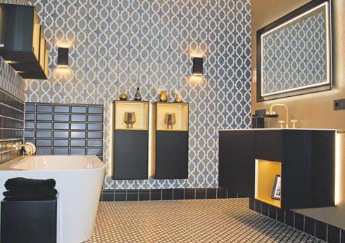 Ein Traum aus Schwarz, Weiß und Gold mit wandhängenden, beleuchteten Badezimmermöbeln, Metrofliesen um die Badewanne und tapezierten Wänden Foto: Elements