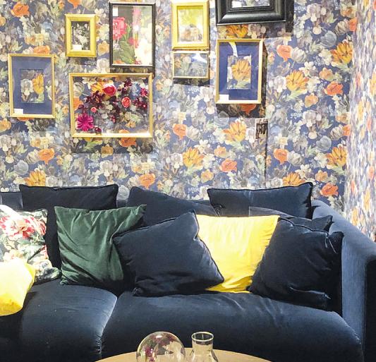 Very british: Ein dunkles Samtsofa vor einer üppigen Blumentapete und vielen kleinen, gerahmten Bildern lässt den Raum kuschelig und gemütlich wirken