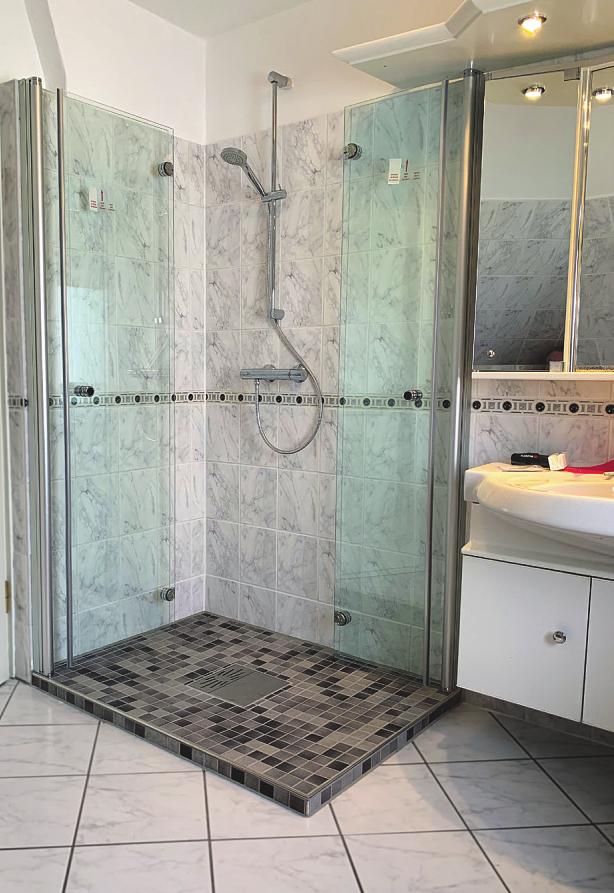 Bodenebene Duschen mit einer Klapp-Faltwand aus Glas sind derzeit Trend und bieten ein größeres Raumgefühl im Bad: Der Clou ist ein gefliester Fußboden mit Bodenablaufpumpe