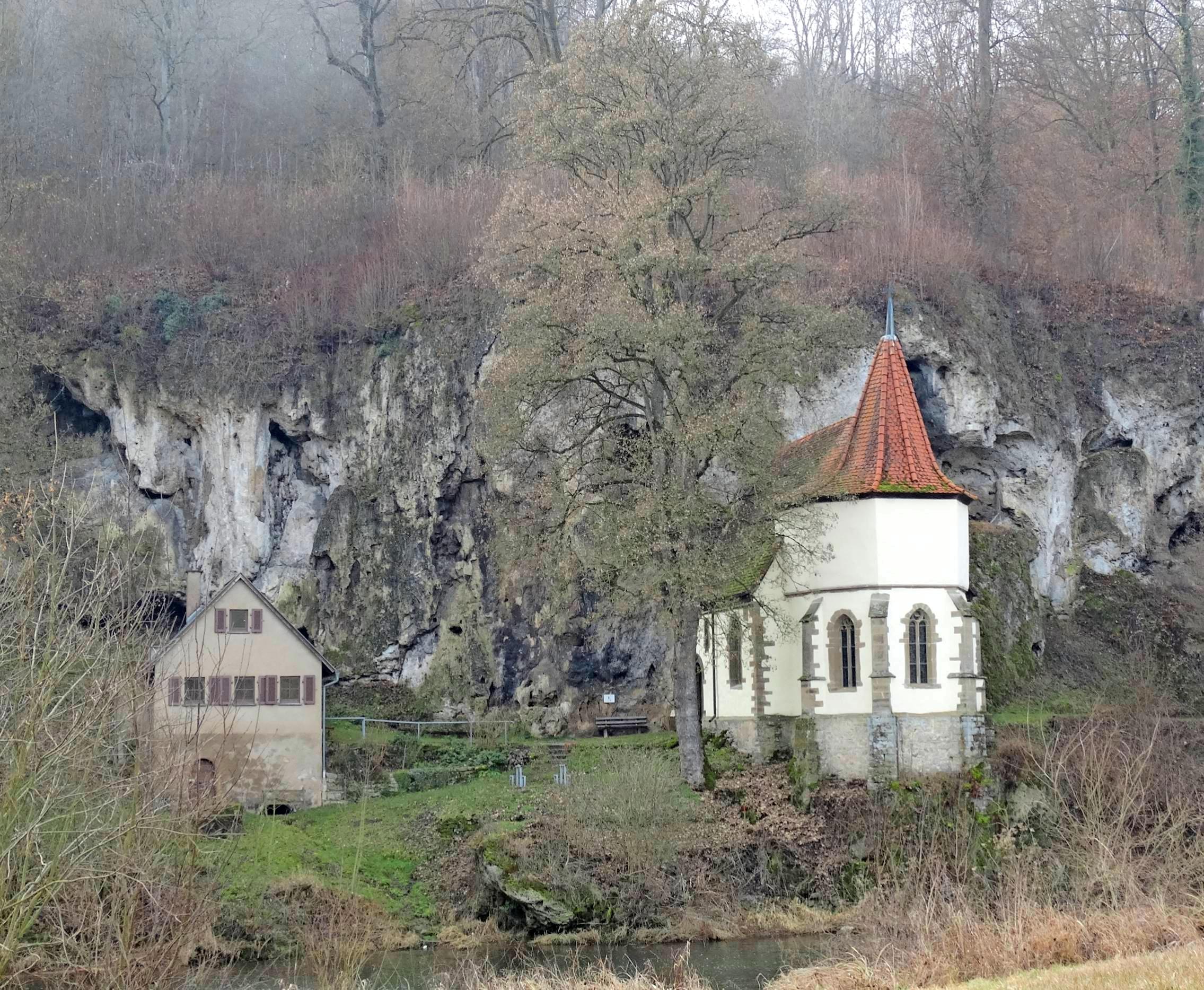 Der Legende nach soll bereits im sechsten Jahrhundert ein Schafhirte am Ufer der Jagst ein Kirchlein errichtet haben. Die jetzige Kapelle im spätgotischen Stil und das Mesnerhaus (links) entstanden zwischen 1511 und 1515. Foto: Ute Böttinger Der Legende nach soll bereits im sechsten Jahrhundert ein Schafhirte am Ufer der Jagst ein Kirchlein errichtet haben. Die jetzige Kapelle im spätgotischen Stil und das Mesnerhaus (links) entstanden zwischen 1511 und 1515. Foto: Ute Böttinger