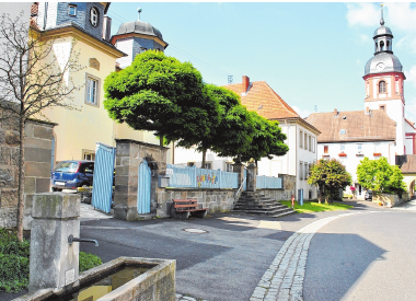 Ortsbildprägende Gebäude im Zentrum von Trappstadt: der Kindergarten (im Bild links) und die Pfarrkirche. Ortsbildprägende Gebäude im Zentrum von Trappstadt: der Kindergarten (im Bild links) und die Pfarrkirche.