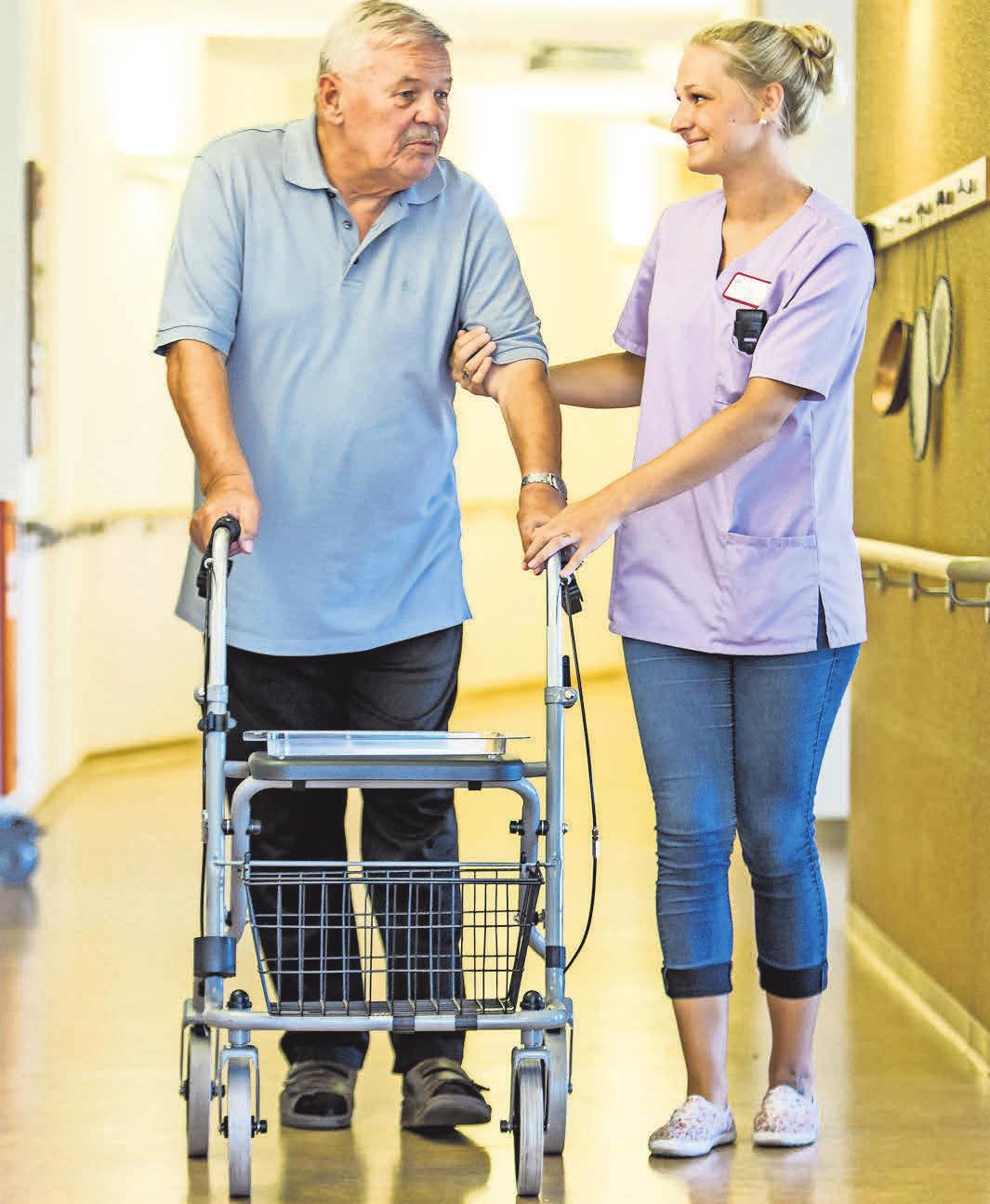 Eine Pflegerin begleitet einen Pflegebedürftigen im Pflegeheim. Eine Pflegerin begleitet einen Pflegebedürftigen im Pflegeheim.