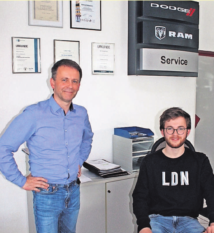 Vor dem Schild der Vertragspartner Dodge und RAM arbeiten im Büro und beraten die Kunden: John Höllerich (rechts), der derzeit eine Ausbildung zum Automobilkaufmann absolviert, und Firmengründer Helmut K. Höllerich. Foto: wb Vor dem Schild der Vertragspartner Dodge und RAM arbeiten im Büro und beraten die Kunden: John Höllerich (rechts), der derzeit eine Ausbildung zum Automobilkaufmann absolviert, und Firmengründer Helmut K. Höllerich. Foto: wb
