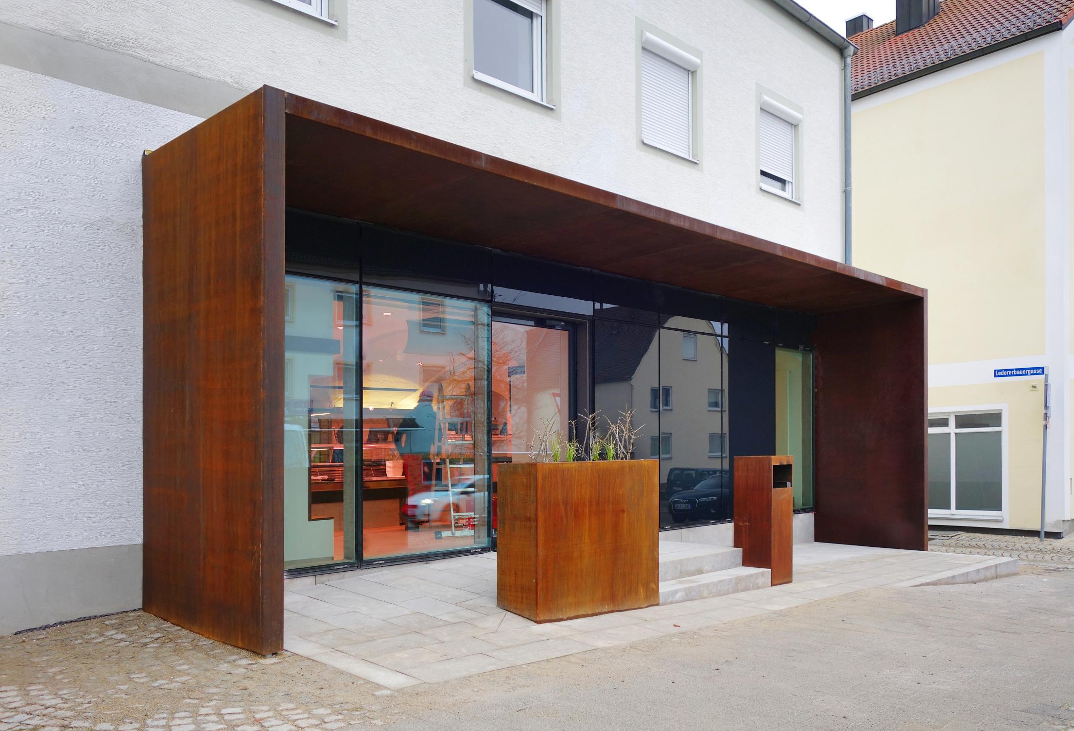 Die Filiale der Metzgerei Pauleser im neuen Design: Der Eingangsbereich erinnert mit seiner Cor-Ten-Stahl-Konstruktion an die Köschinger Tore im Kreisverkehr am nordwestlichen Ortseingang. Die große Glasfront lässt viel Licht ins Innere fluten. Die Filiale der Metzgerei Pauleser im neuen Design: Der Eingangsbereich erinnert mit seiner Cor-Ten-Stahl-Konstruktion an die Köschinger Tore im Kreisverkehr am nordwestlichen Ortseingang. Die große Glasfront lässt viel Licht ins Innere fluten.