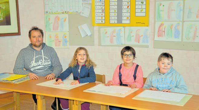 Die dritte Klasse behandelt den Schöpfungsbericht. Heilpädagoge Christopher Winkelmann (v.li.n.re.) und seine Schüler Emilia (9), Amelie (10) und Mika (9) sind stolz auf ihre zum Thema passenden Schreibübungen. FOTO: REG Die dritte Klasse behandelt den Schöpfungsbericht. Heilpädagoge Christopher Winkelmann (v.li.n.re.) und seine Schüler Emilia (9), Amelie (10) und Mika (9) sind stolz auf ihre zum Thema passenden Schreibübungen. FOTO: REG