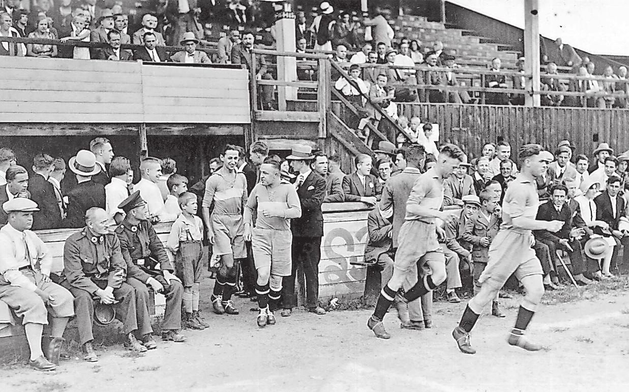 Da kommen sie: Zuschauer auf und vor der ersten Tribüne im Stadion Brötzinger Tal sehen, wie die Spieler vor einer Partie im Jahre 1931 den Platz betreten. ARCHIVFOTO: PZ-ARCHIV  